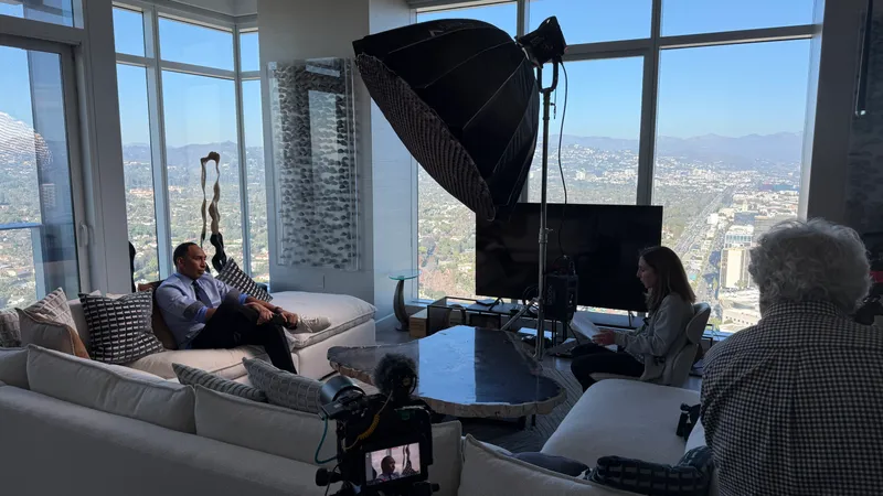 A camera and softbox set up for an interview beside windows overlooking the city