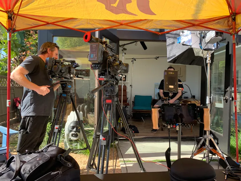 Cameras and a seated interview subject under a canopy on location