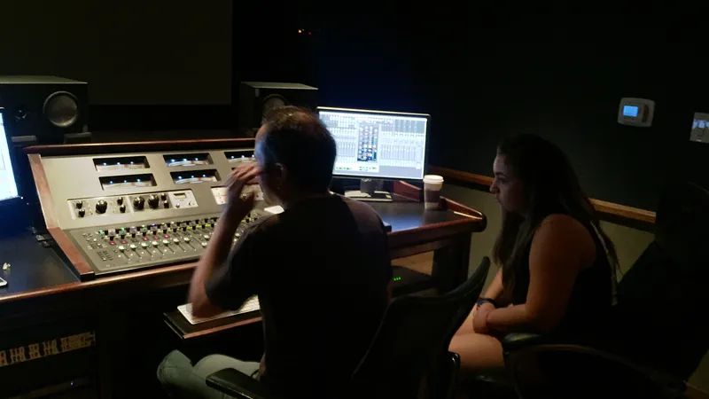 Two collaborators working at a mixing console in a sound studio