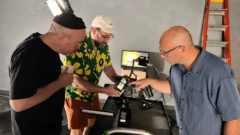 Three collaborators checking a camera on set